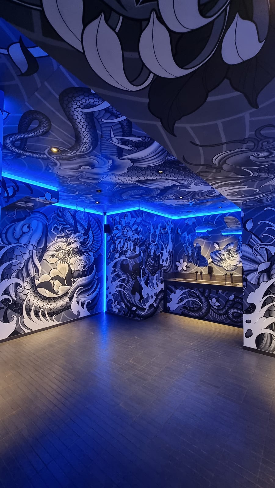 A room at Koyasan wrapped in a black and white dragon mural, its walls and ceiling edged in blue light.